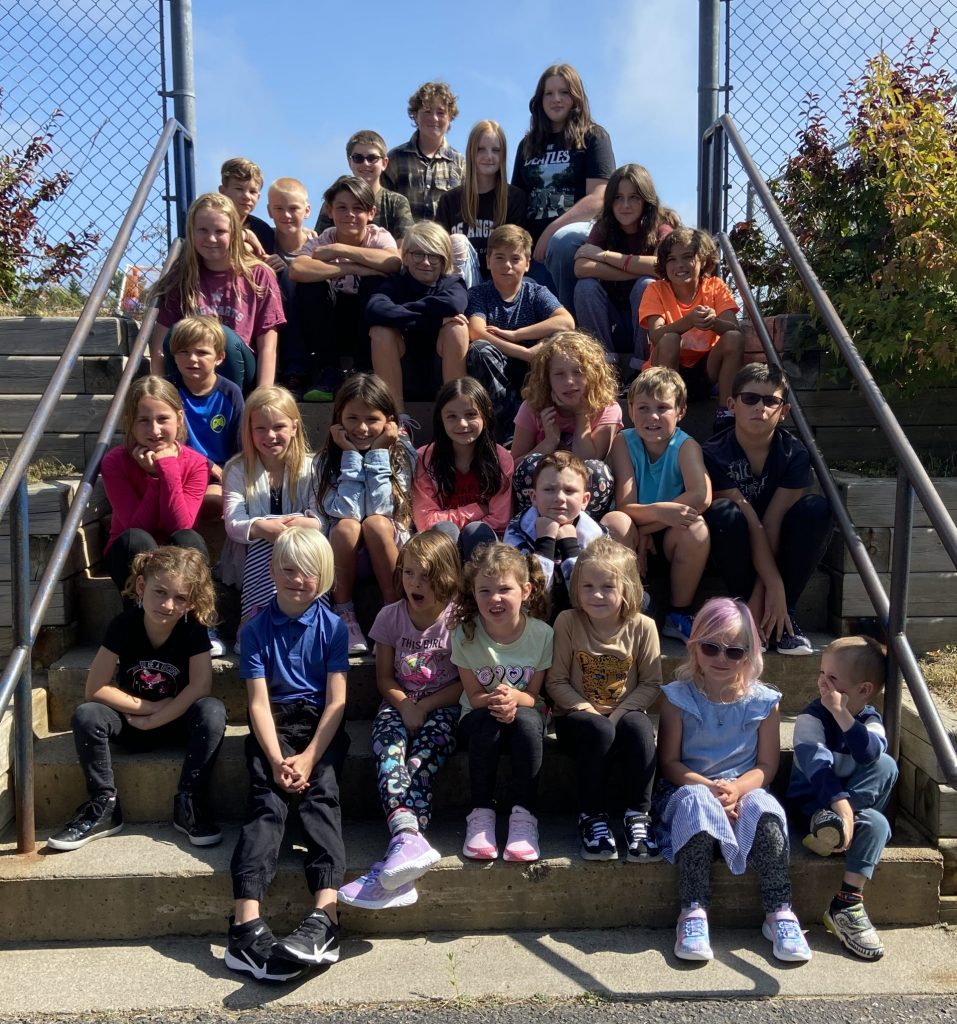 Une trentaine d’élèves de la maternelle à la 8e année sont assis dans un escalier à l’extérieur. Ils sont posés pour une photo de groupe.